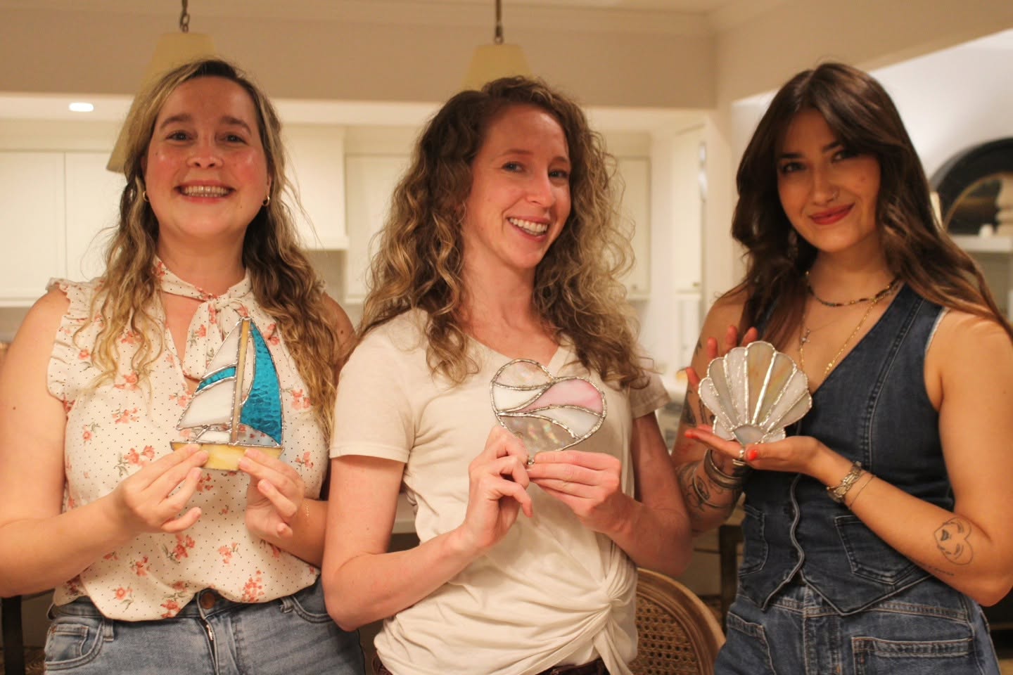 Clients showing off their finished stained-glass pieces at a workshop